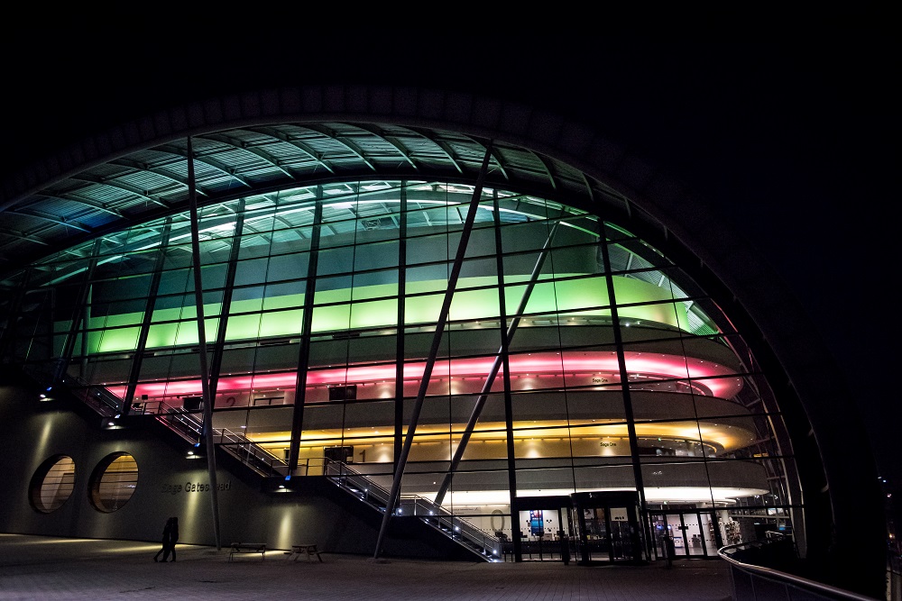 Sage at night. Photo from the outside with horizontal bands of colour: blue, green, red and yellow.